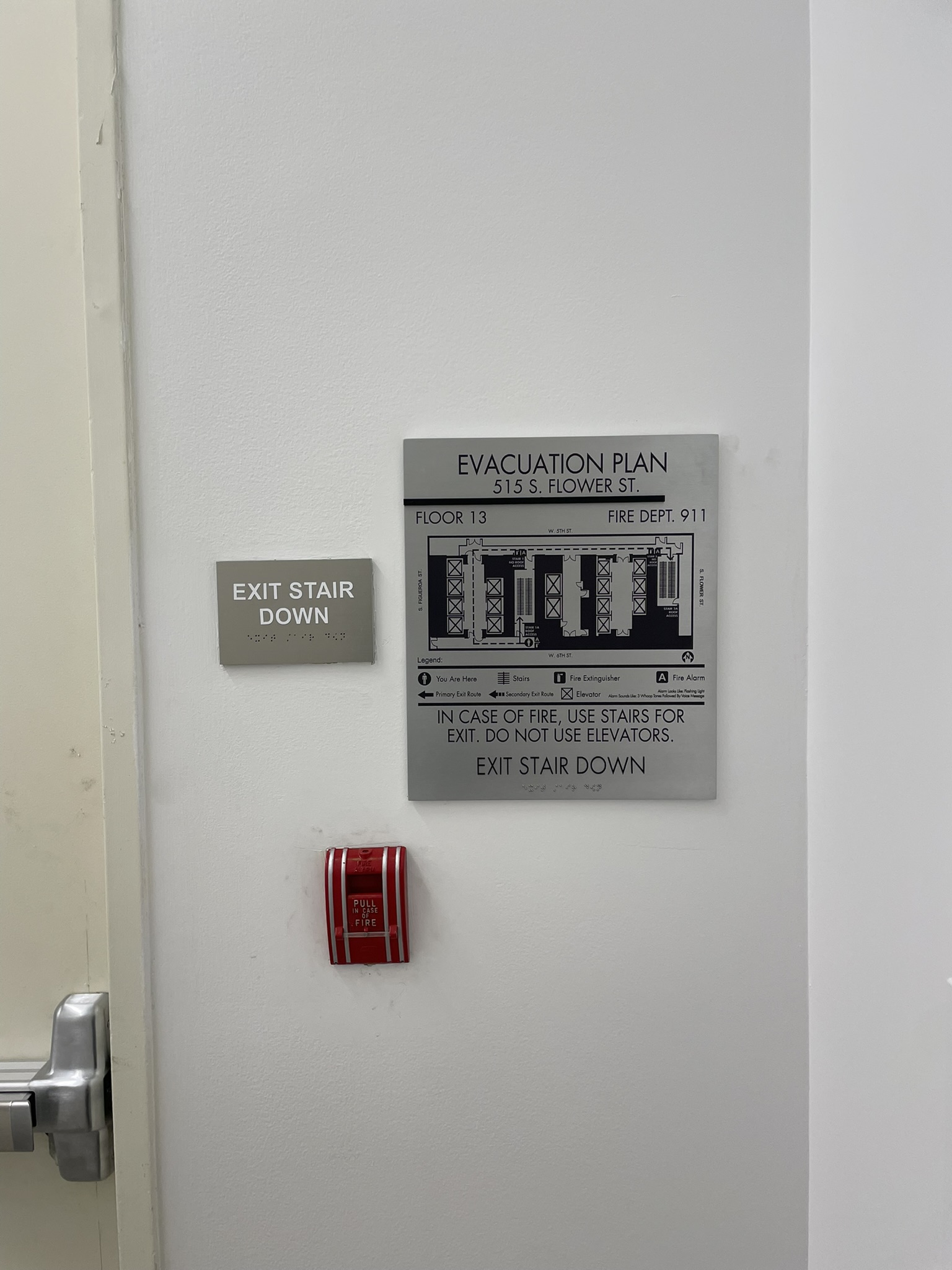 Gray evacuation map for floor 13 beside an Exit Stair Down sign with braille