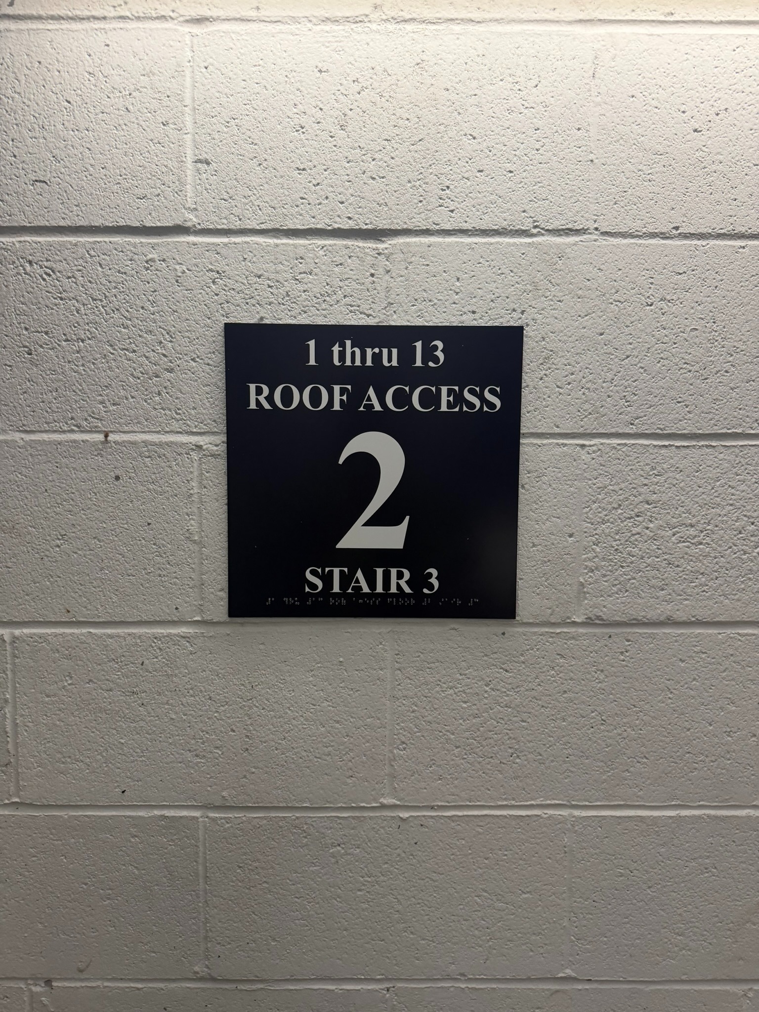 Dark stairwell identification sign with floor number 2, Stair 3, roof-access information, and braille