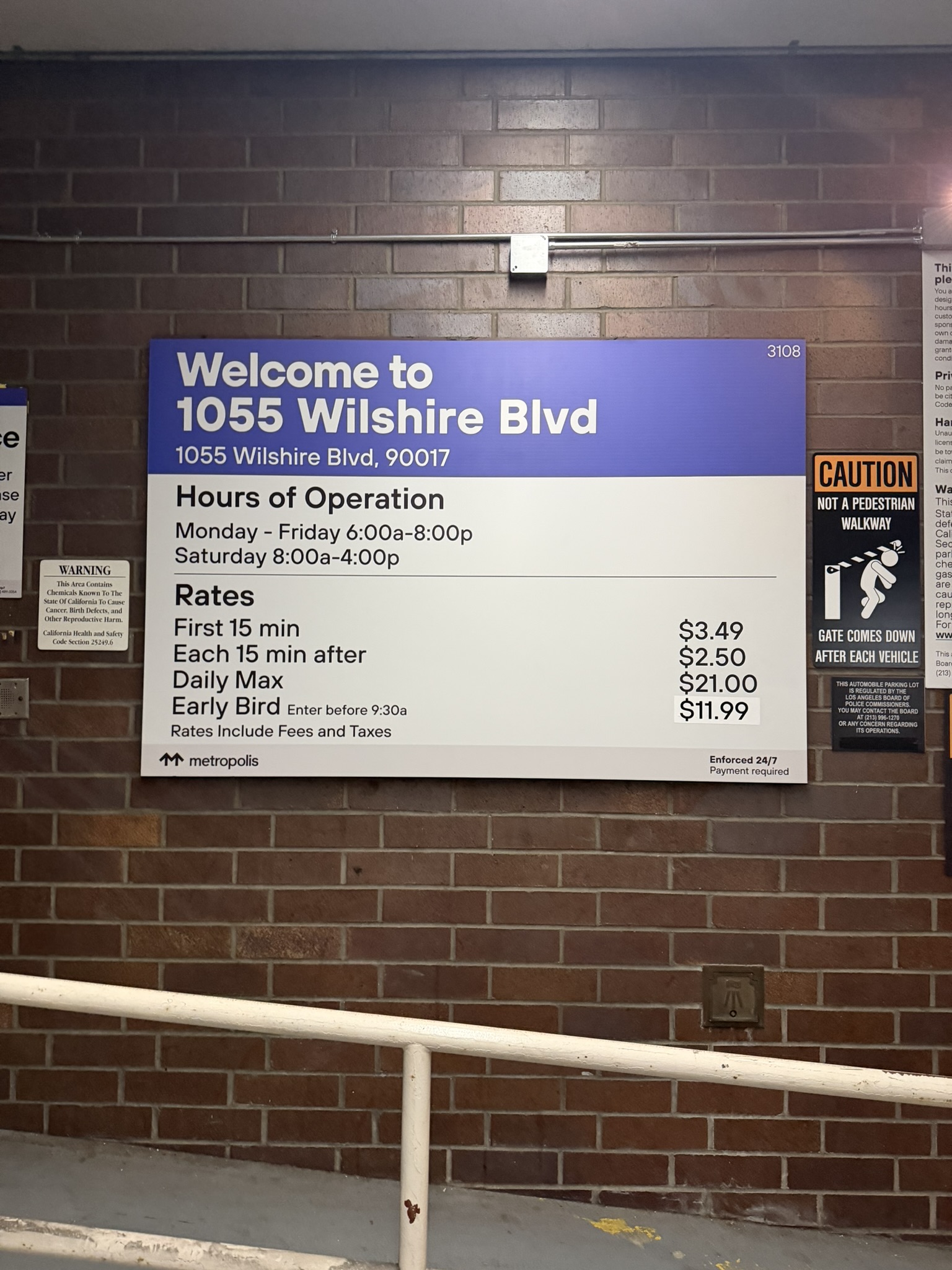 Purple and white parking rate sign for 1055 Wilshire Boulevard mounted on a brick wall